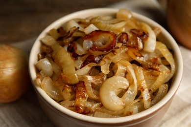 Photo of Tasty fried onion in ceramic bowl, closeup