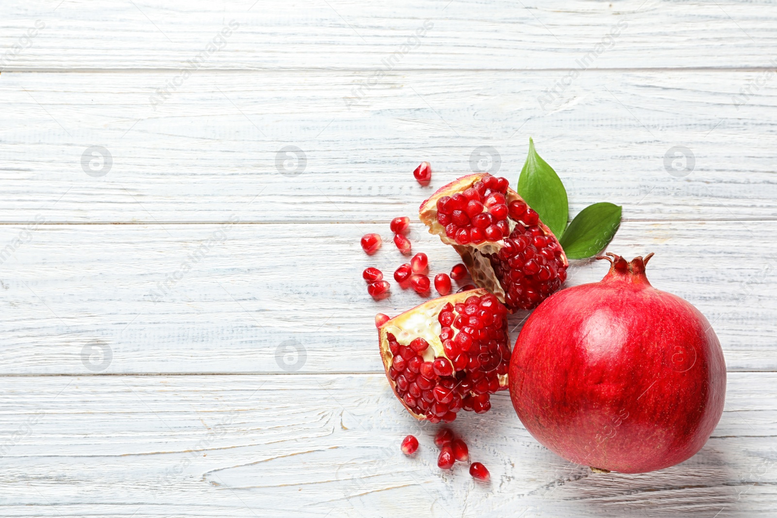 Photo of Flat lay composition with ripe pomegranates and space for text on white wooden background