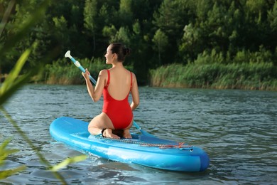 Photo of Woman paddle boarding on SUP board in river, back view