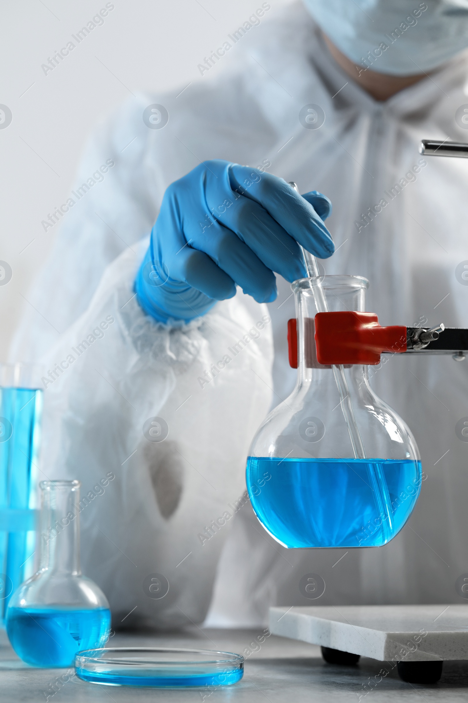 Photo of Scientist taking sample of light blue liquid in laboratory, closeup