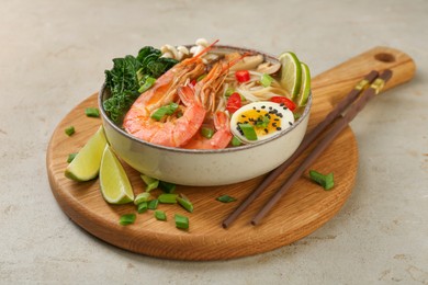 Delicious ramen with shrimps, egg in bowl and chopsticks on light textured table. Noodle soup