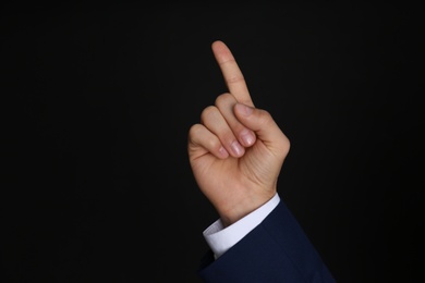 Photo of Businessman pointing at something on black background, closeup. Finger gesture