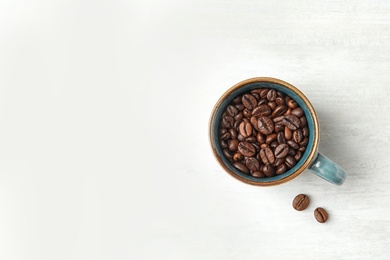 Photo of Cup with roasted coffee beans on white background, top view