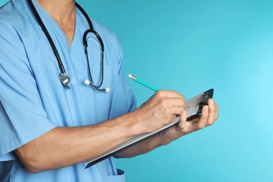 Male doctor with stethoscope and clipboard on color background, closeup. Medical objects