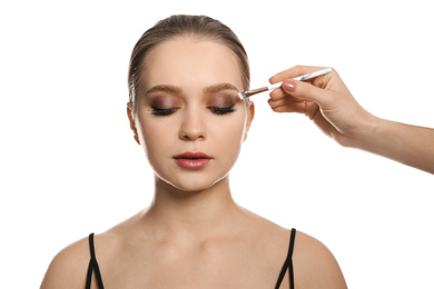 Photo of Artist applying makeup onto woman's face on white background