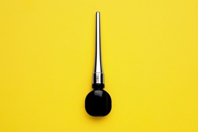 Photo of Black eyeliner on yellow background, top view. Makeup product