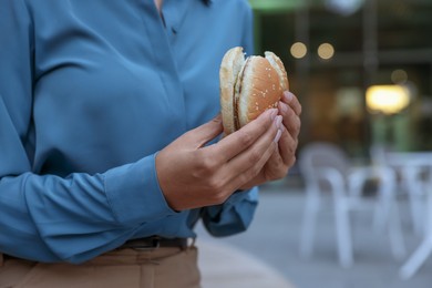 Lunch time. Businesswoman with hamburger outdoors, closeup. Space for text