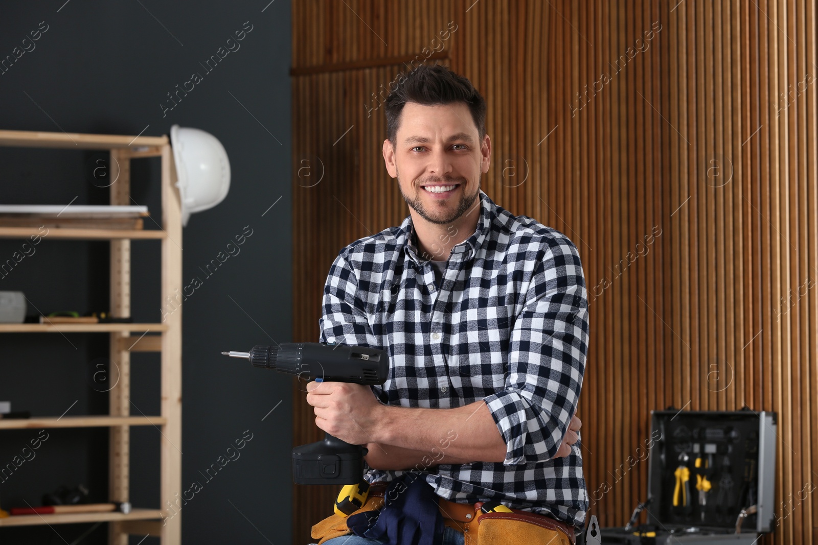 Photo of Handsome working man with electric screwdriver indoors. Home repair