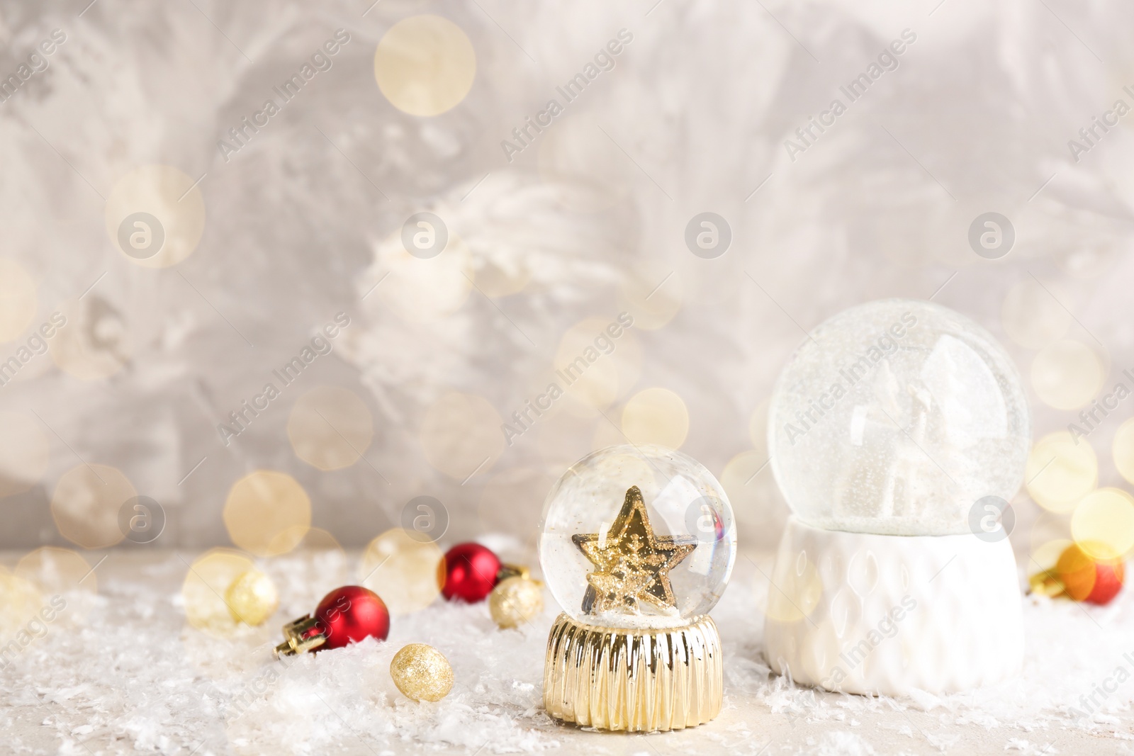 Image of Beautiful Christmas snow globes and ornaments on light table, bokeh effect. Space for text