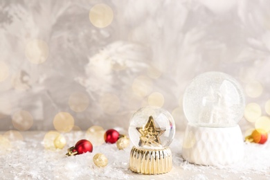 Image of Beautiful Christmas snow globes and ornaments on light table, bokeh effect. Space for text