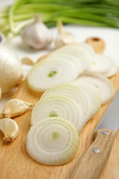 Garlic and cut onion on wooden board, closeup