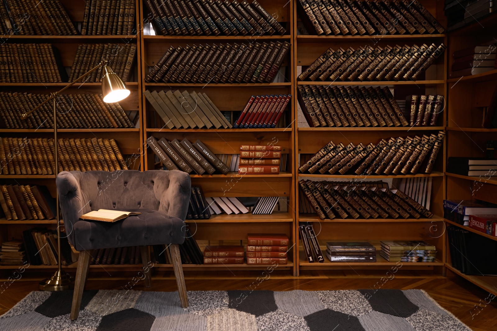 Photo of Cozy home library interior with comfortable armchair and collection of vintage books on shelves