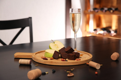 Photo of Delicious brunost cheese, apple and glass of champagne on table