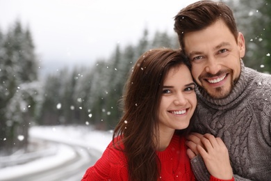 Photo of Cute couple outdoors on snowy day, space for text. Winter vacation