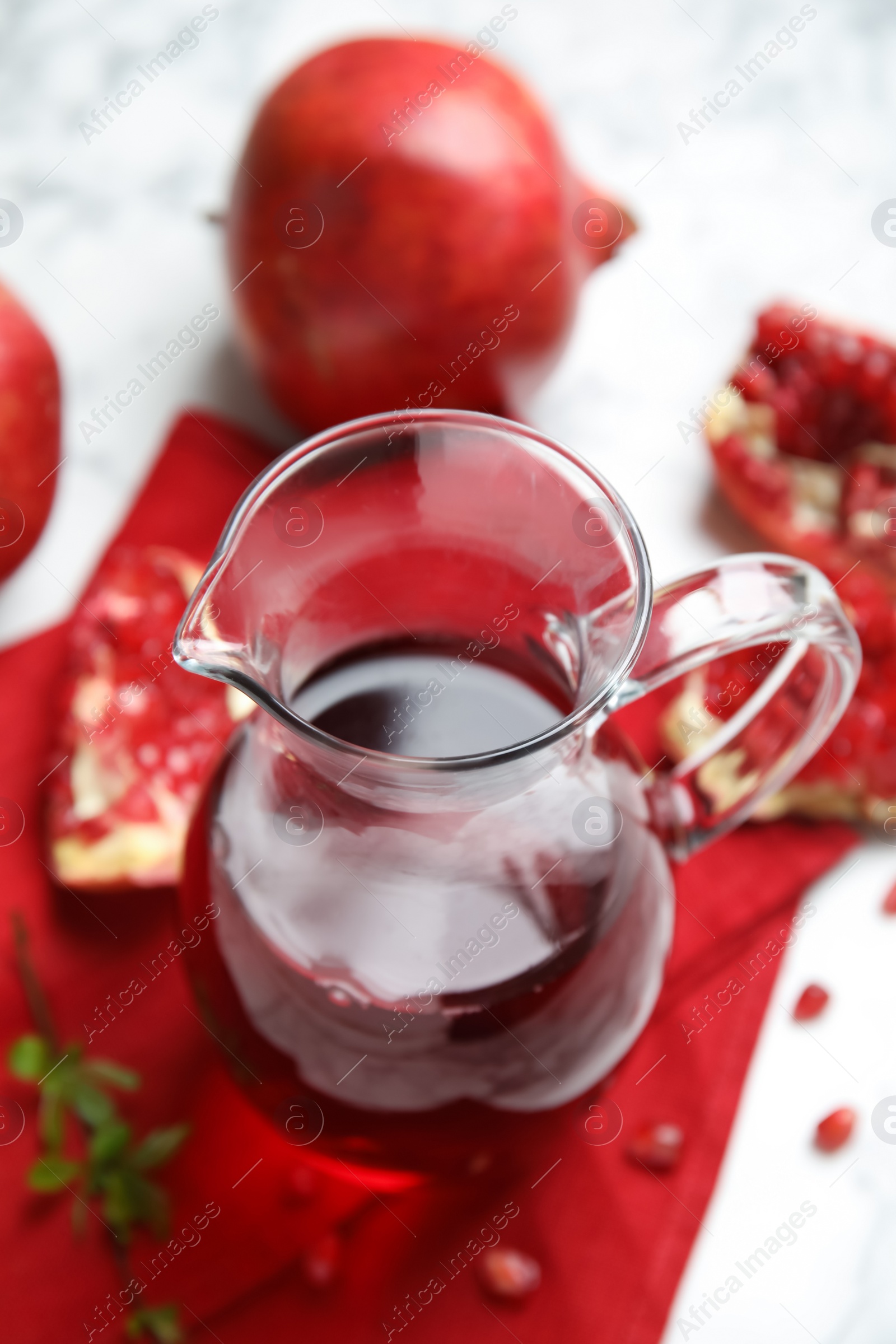 Photo of Pomegranate juice in jug and fresh fruits on white table
