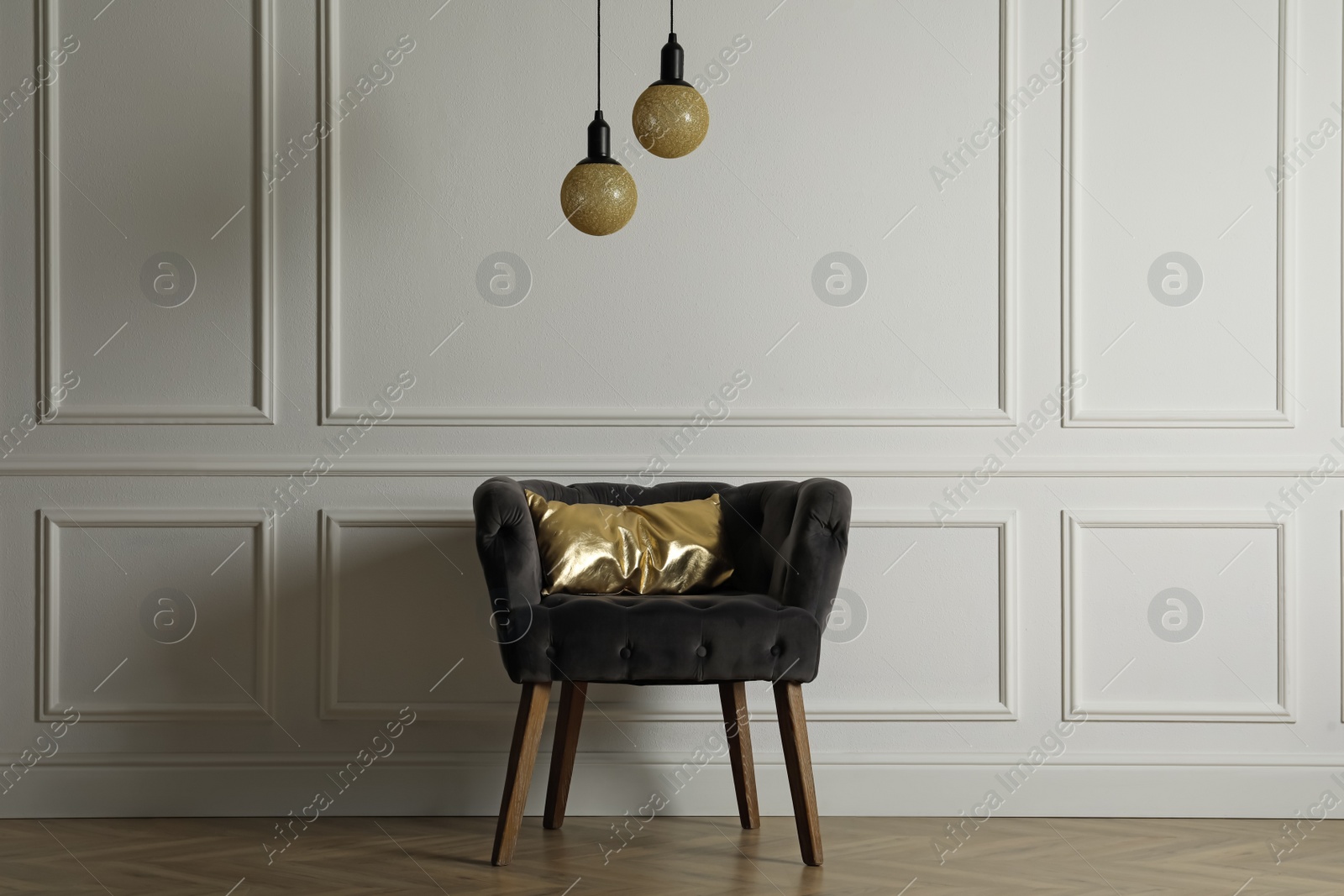 Photo of Stylish armchair with cushion near white wall indoors. Interior design
