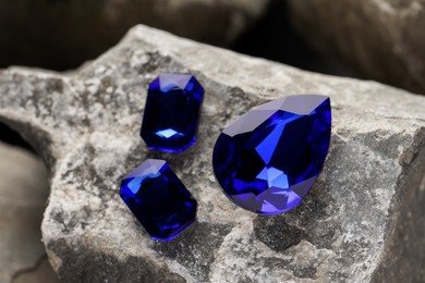 Photo of Three beautiful blue gemstones for jewelry on stone surface, closeup