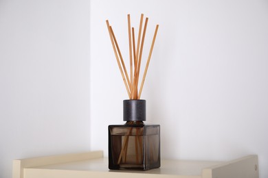 Photo of Aromatic reed freshener on wooden table near white wall