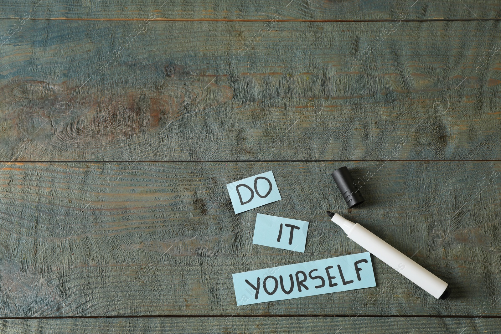 Photo of Phrase Do It Yourself and marker on grey wooden table, flat lay with space for text. DIY concept