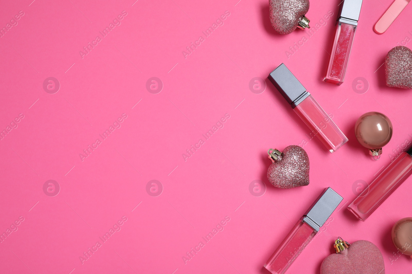 Photo of Lip glosses and Christmas ornaments on pink background, flat lay