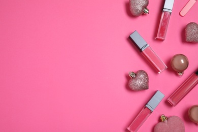 Lip glosses and Christmas ornaments on pink background, flat lay