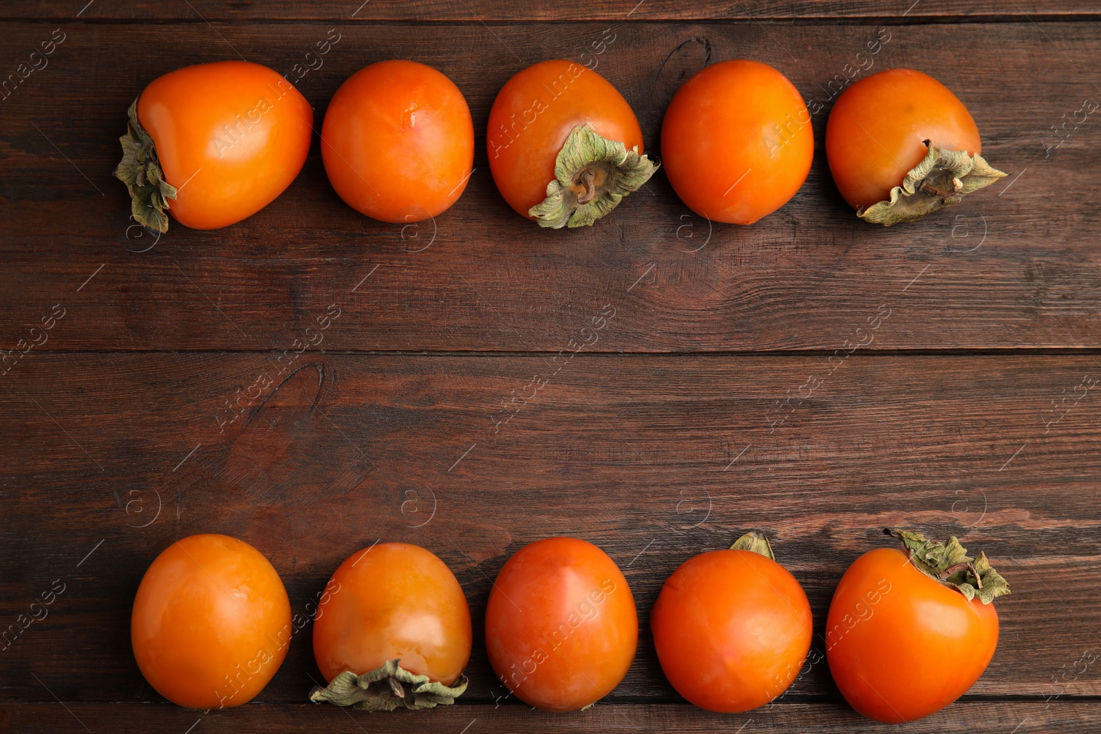 Photo of Delicious fresh persimmons on wooden table, flat lay. Space for text