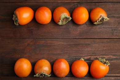 Delicious fresh persimmons on wooden table, flat lay. Space for text