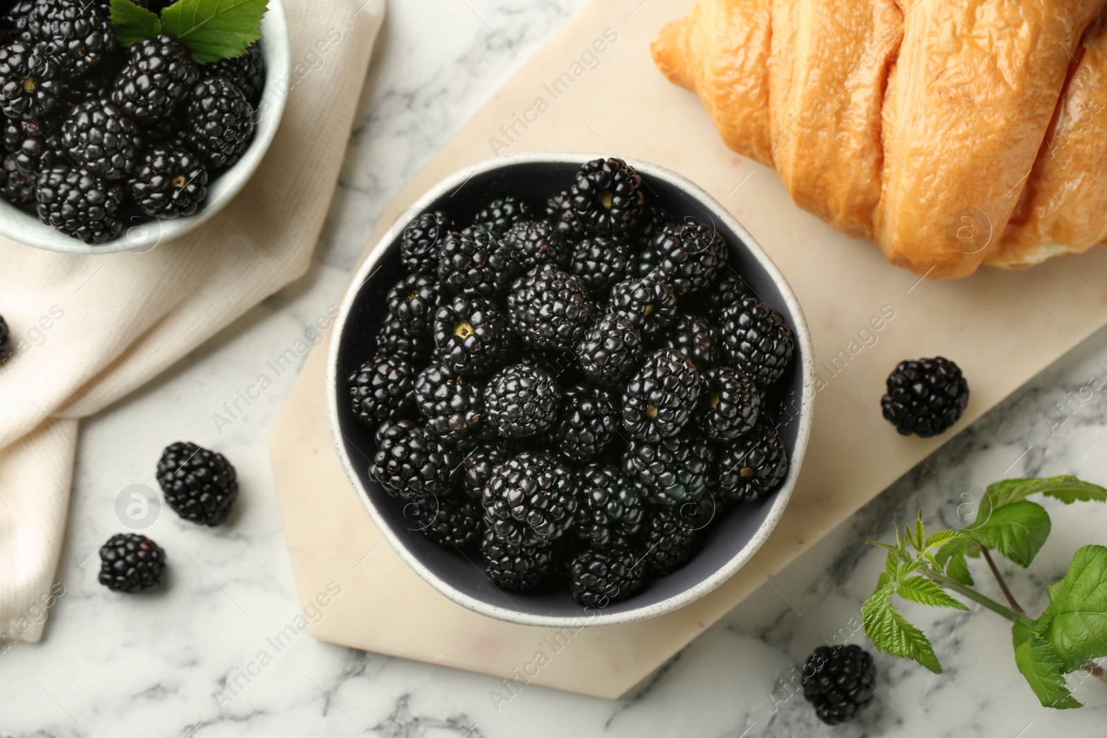 Photo of Bowl of fresh ripe blackberries on white marble table, flat lay
