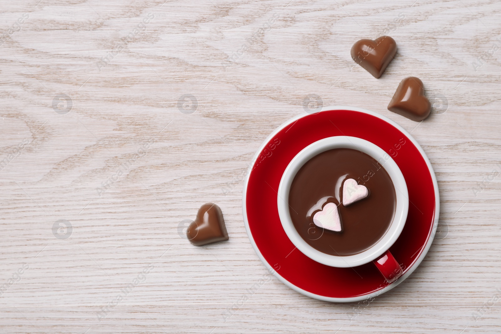 Photo of Cup of hot chocolate with heart shaped marshmallows and tasty candies on white wooden table, flat lay. Space for text