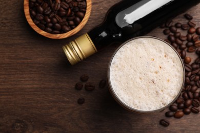 Bottle of delicious syrup, glass of coffee and beans on wooden table, flat lay. Space for text