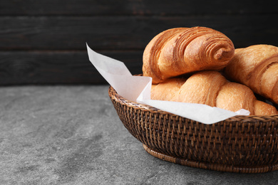 Photo of Tasty fresh croissants on grey table, closeup. Space for text