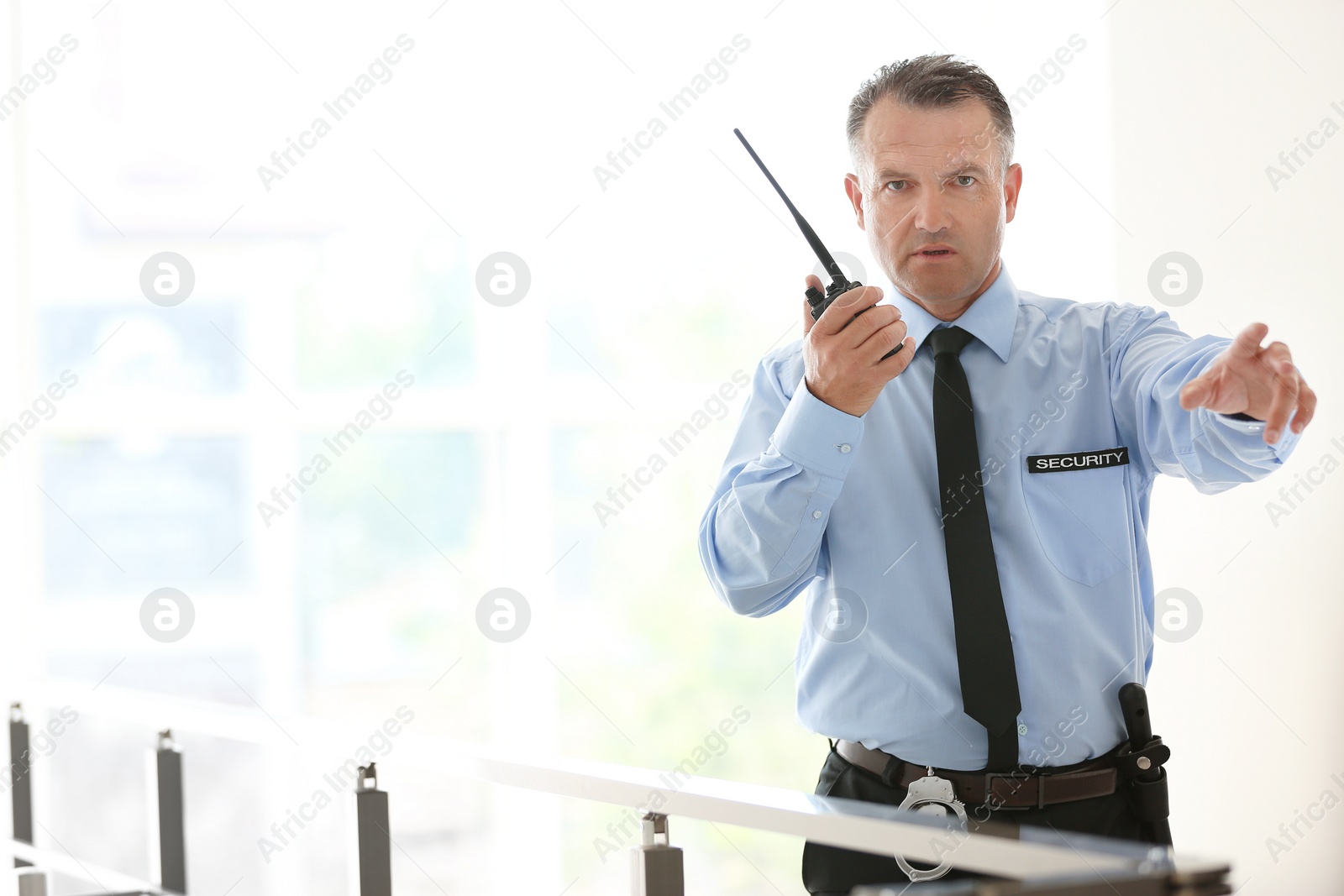 Photo of Male security guard using portable radio transmitter indoors