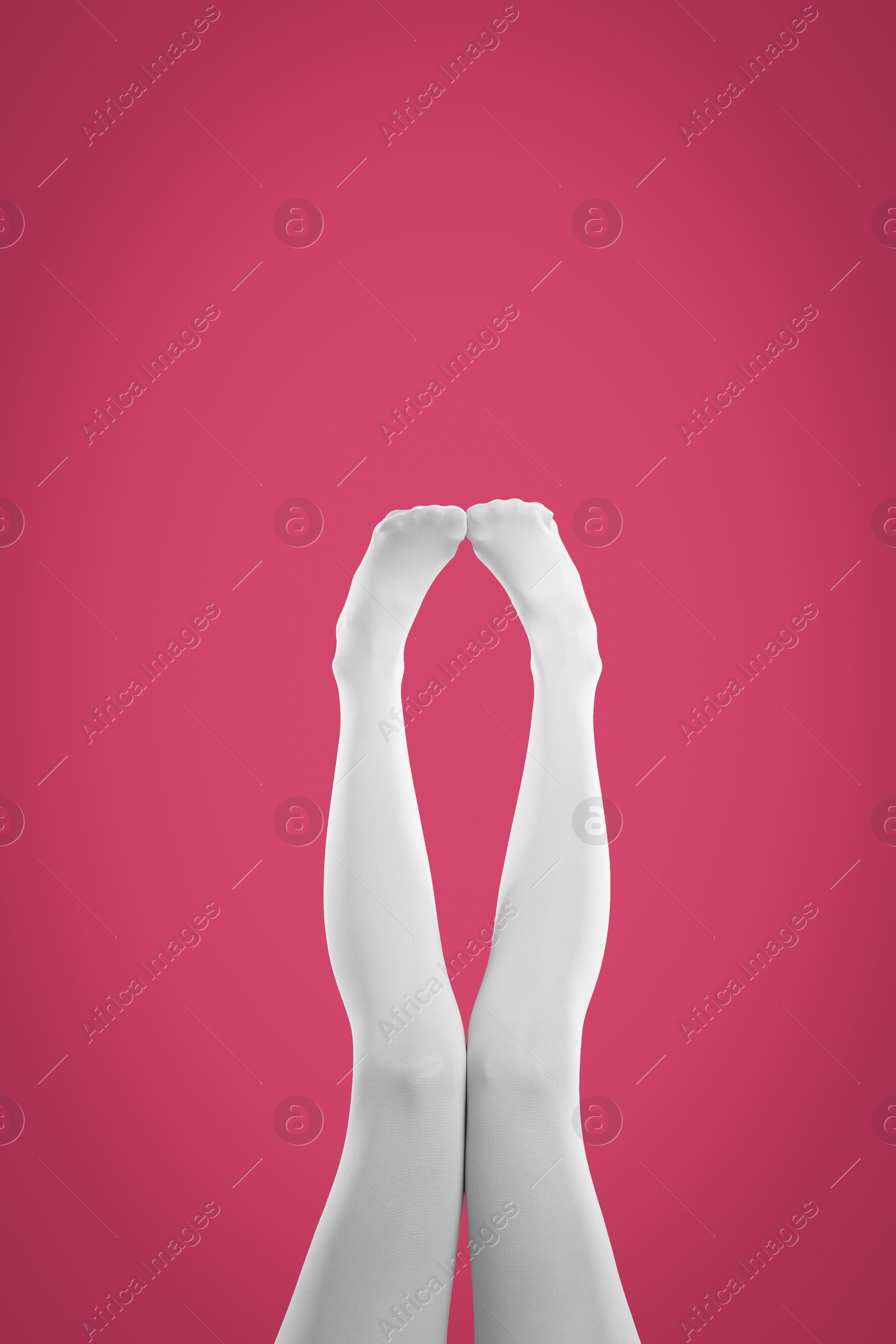 Photo of Woman wearing white tights on crimson background, closeup of legs