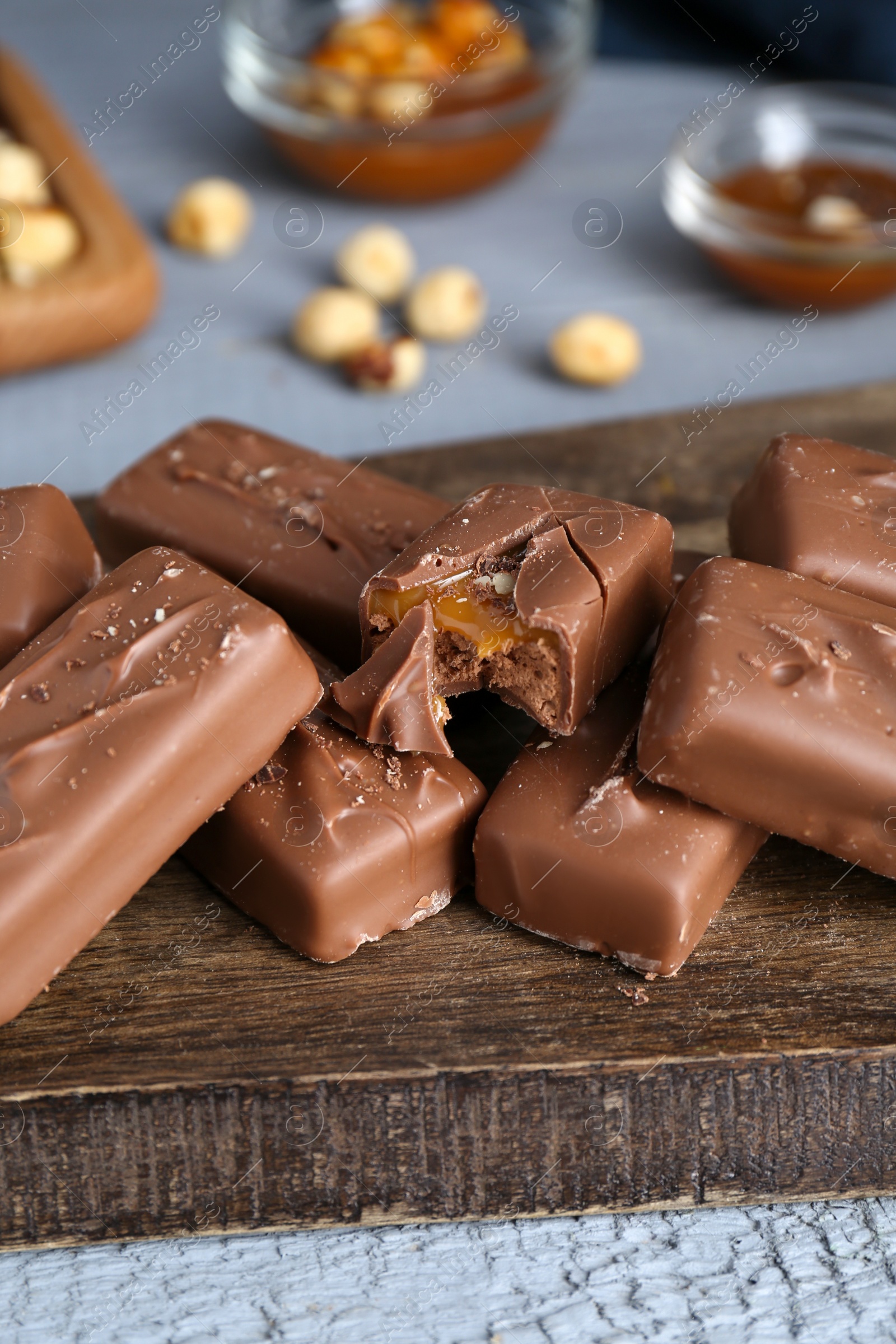 Photo of Delicious chocolate candy bars with caramel and nuts on grey wooden table