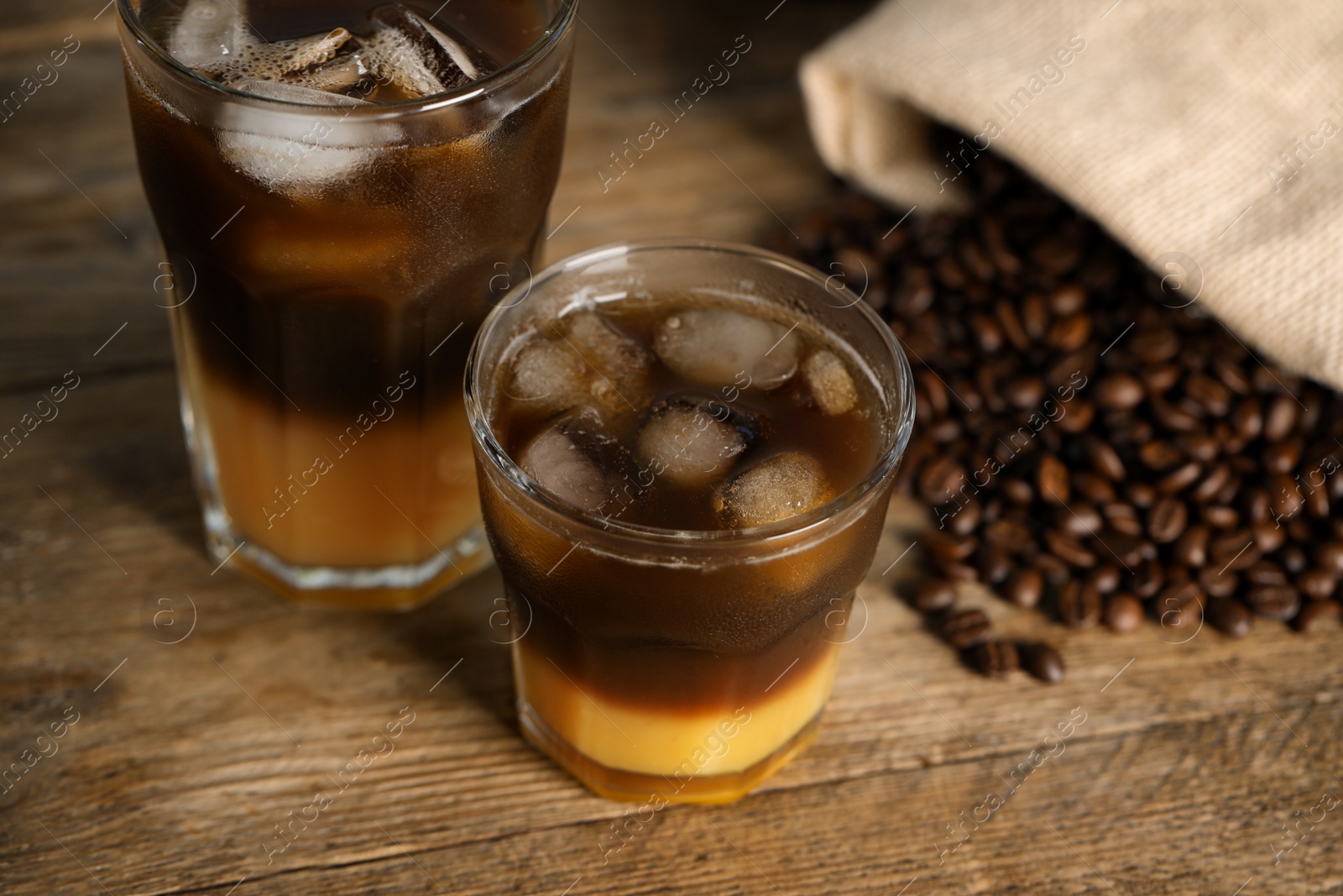 Photo of Tasty refreshing drink with coffee and orange juice on wooden table