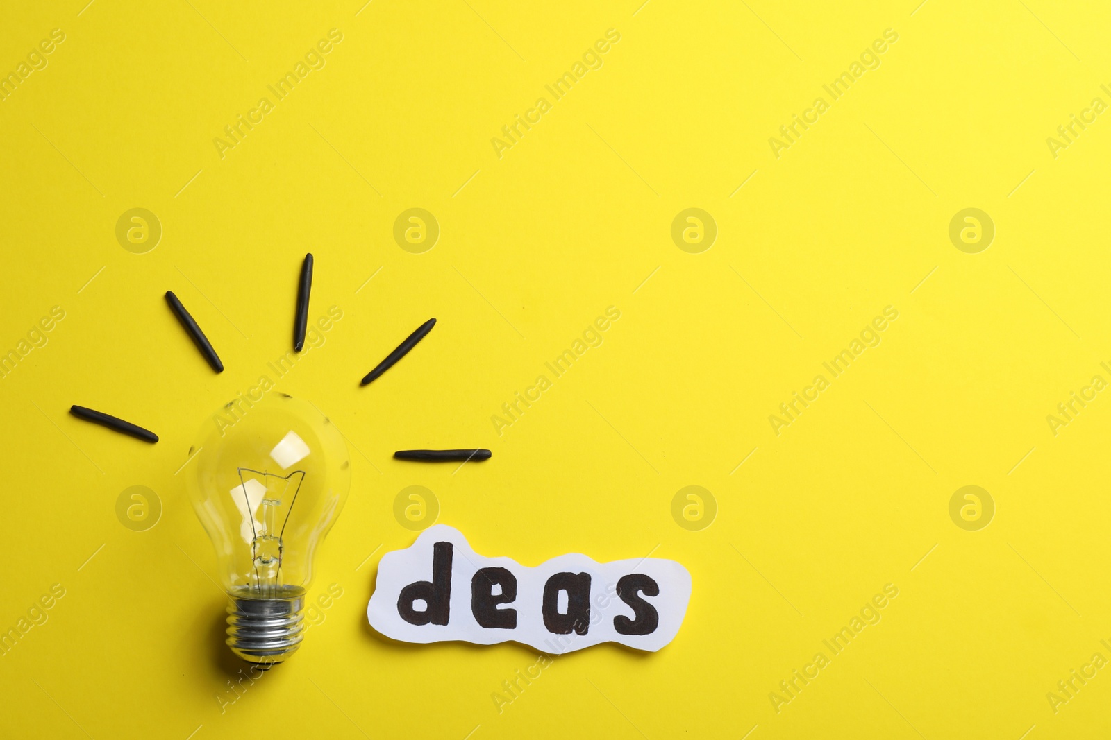 Photo of Word Ideas made with lightbulb and paper sheet on yellow background, flat lay. Space for text