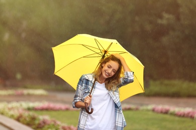 Happy young woman with umbrella under rain in park