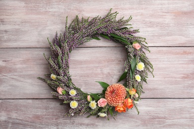 Photo of Beautiful autumnal wreath with heather flowers on light wooden background, top view. Space for text