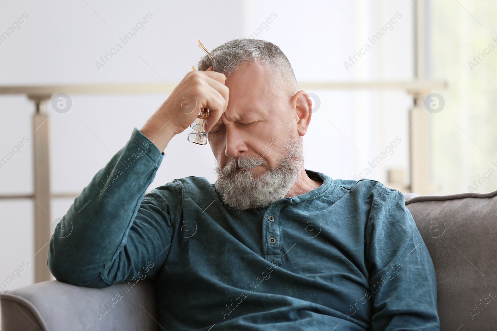 Photo of Depressed senior man sitting in armchair indoors