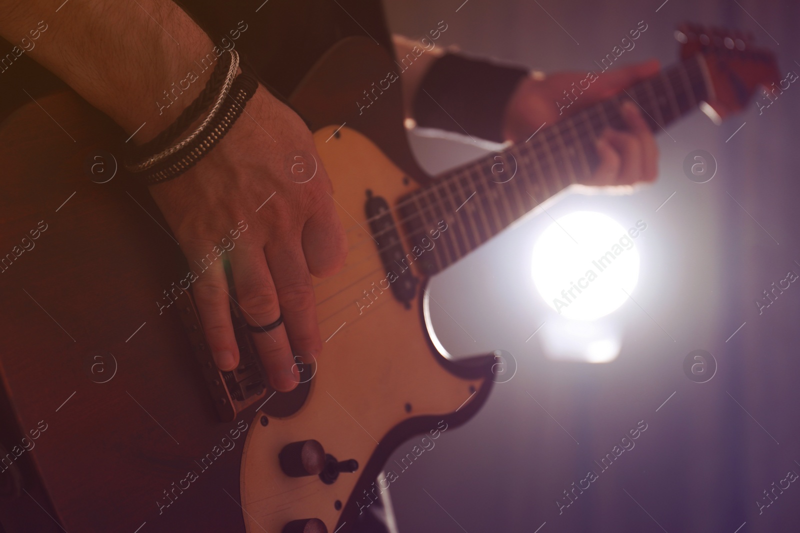 Photo of Man playing electric guitar on stage, closeup. Rock music