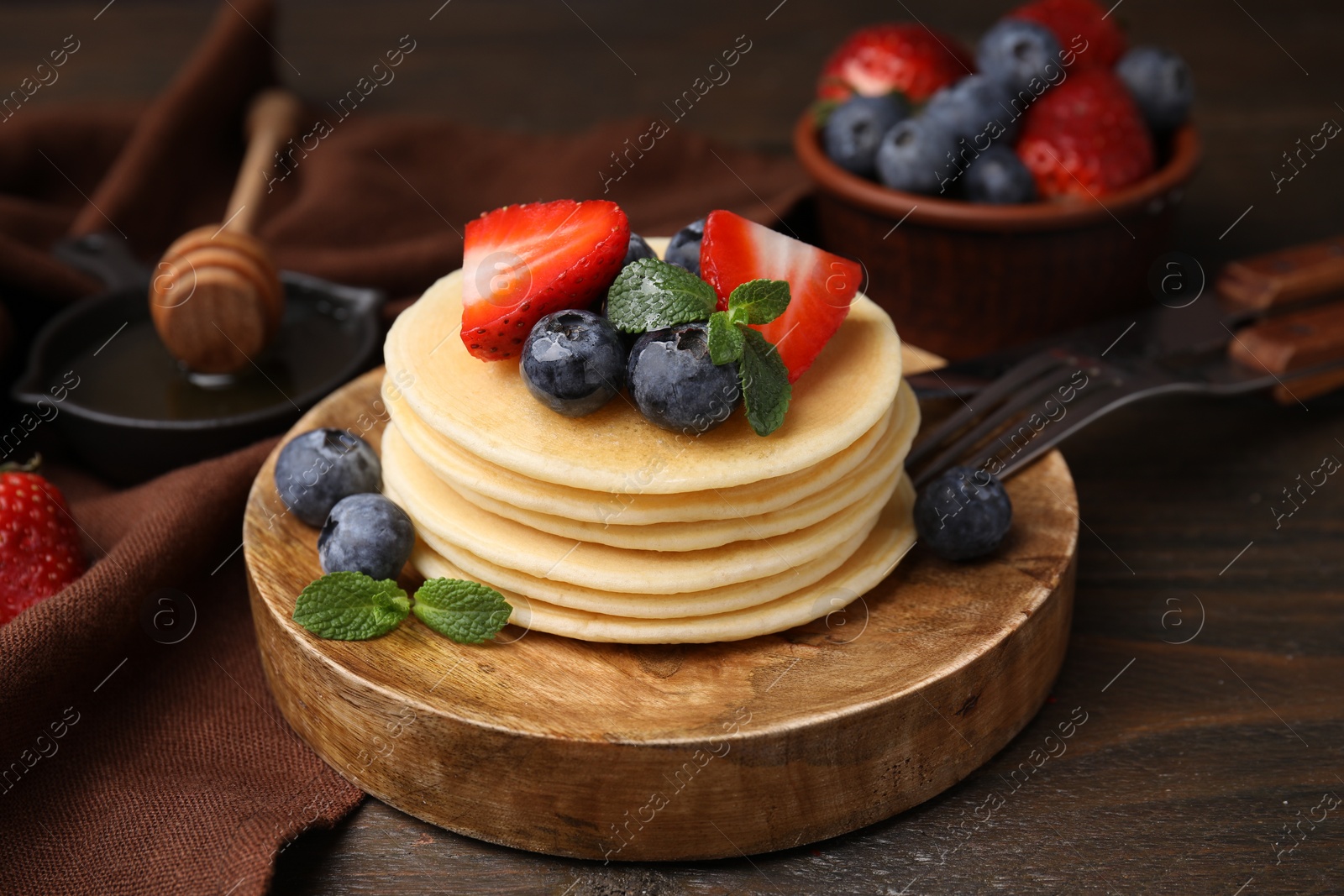 Photo of Delicious pancakes with strawberries, blueberries and mint on wooden table, closeup