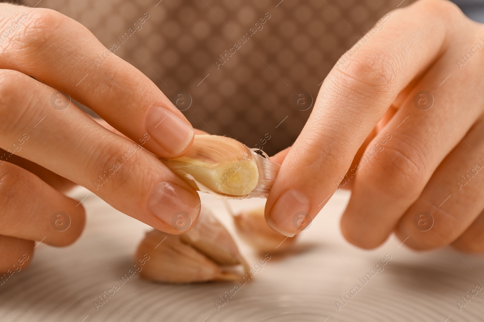 Photo of Woman peeling fresh garlic at table, selective focus