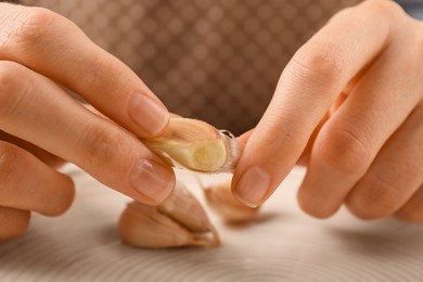 Woman peeling fresh garlic at table, selective focus