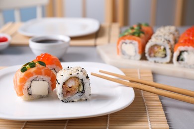 Different tasty sushi rolls and chopsticks on table