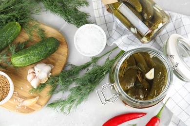 Photo of Flat lay composition with jars of pickled cucumbers on light table