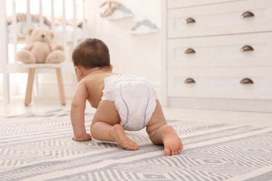 Photo of Cute baby crawling on floor at home, back view
