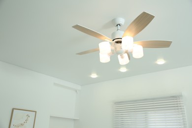 Photo of Ceiling fan with lamps indoors, low angle view