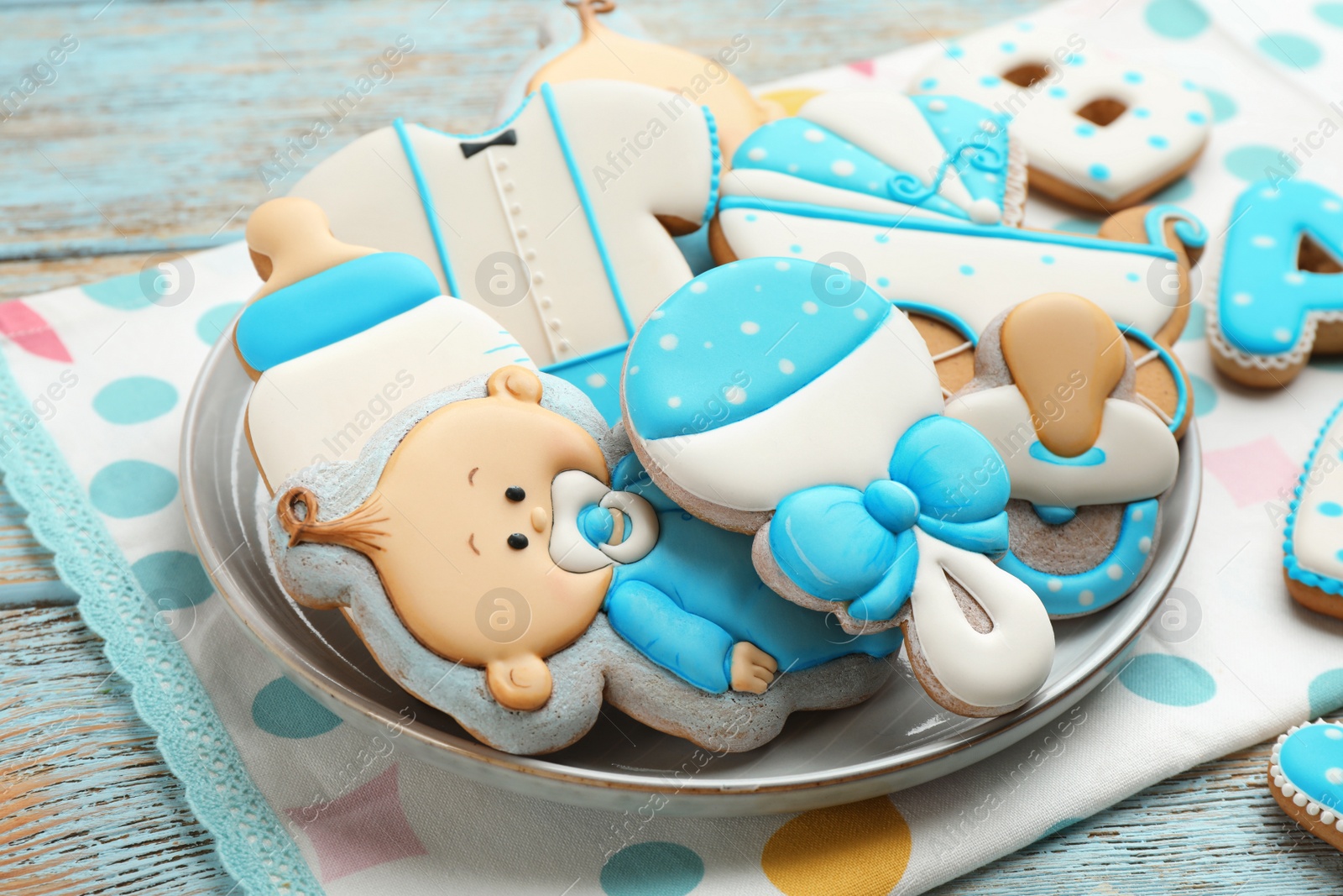 Photo of Cute tasty cookies of different shapes on light blue wooden table, closeup. Baby shower party