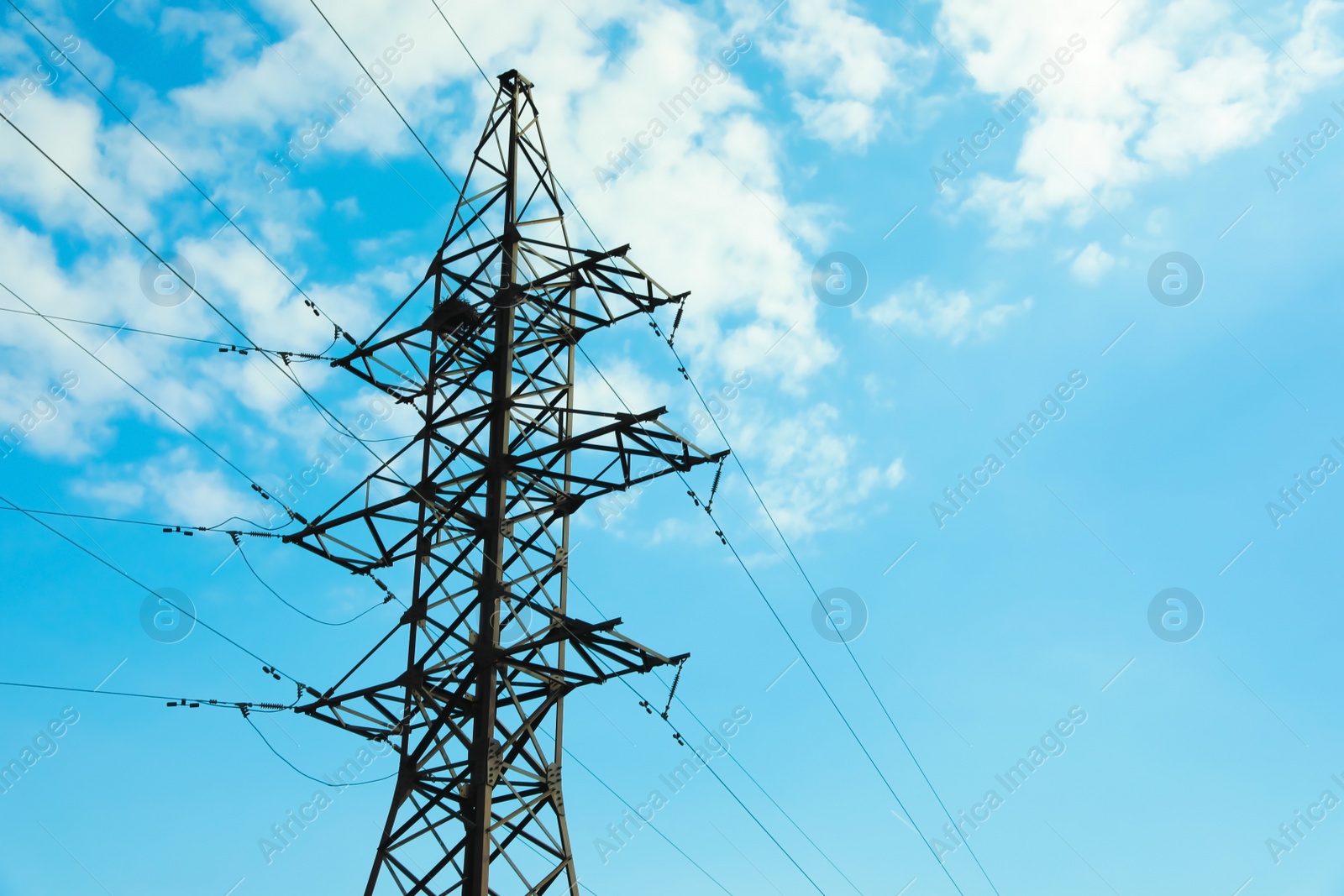 Photo of Telephone pole and wires against blue sky with clouds