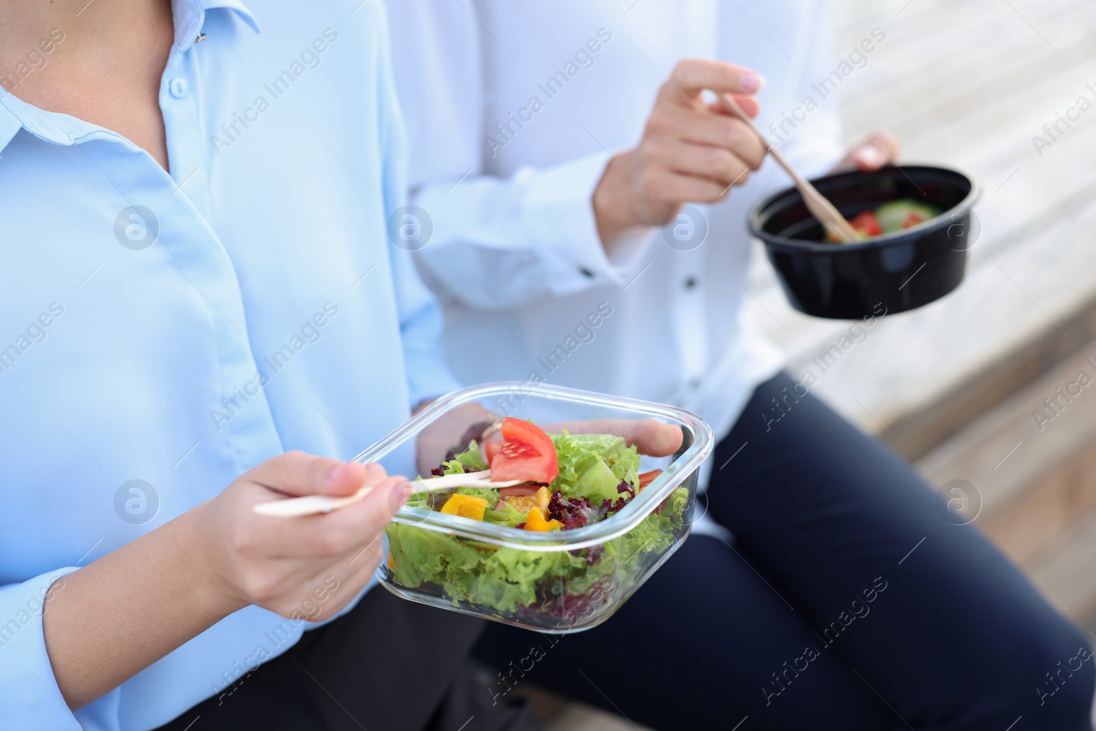 Photo of Business people eating from lunch boxes outdoors, closeup